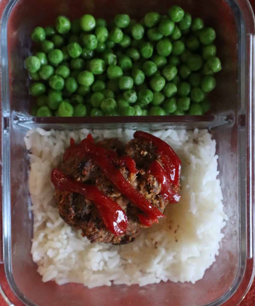 Photo of a gluten free meatloaf muffin meal prepped with rice and peas in a glass meal prep container