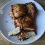 A photo of two baked boneless skinless chicken thighs on a white plate